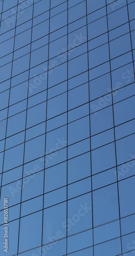 Wallpaper Mural Modern glass building reflects sky in bright sunlight. Scene shows clean geometry and corporate style. Blue facade creates minimal mood. View points upward. Building architecture feels modern.Vertical Torontodigital.ca