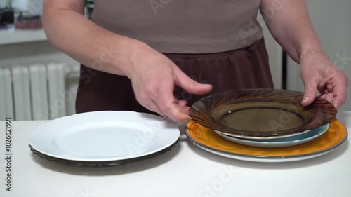 A man places various plates on the table. Plates of different colors and designs highlight the creative approach to table decor.