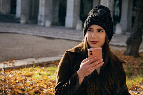 Mujer joven grabando o enviando un mensaje de audio en su teléfono móvil al aire libre.