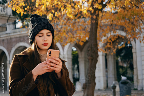 Mujer joven enviando mensajes de texto mientras disfruta de un descanso en el parque.