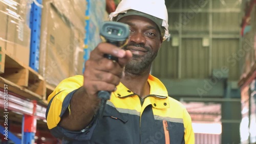 Joyful work African American male store clerk wearing hard hat stands inspecting the shelves smiling with his arms crossed looking at camera being stored in an orderly manner for safe handling.