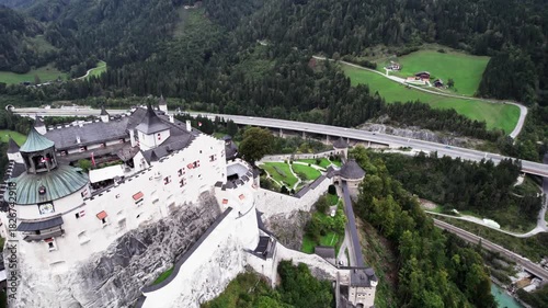 Drone turn above Werfen Castle toward courtyard with motorway in background

