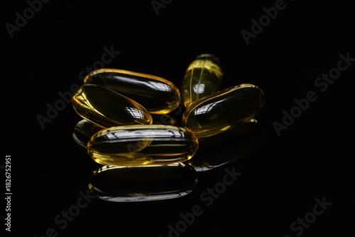 Gelbe Weichkapseln auf schwarzem Spiegeluntergrund