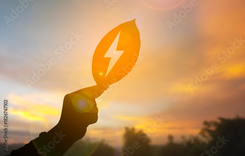 Sustainable Energy Concept with Leaf and Lightning Symbol Silhouette at Sunset
