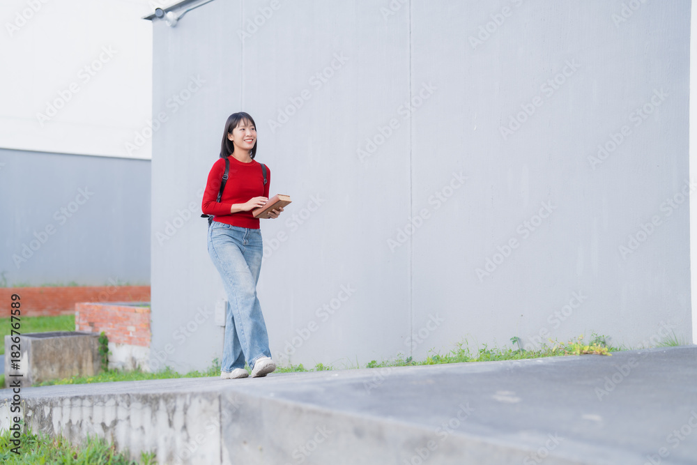 Fototapeta premium Asian student walking on campus carrying books