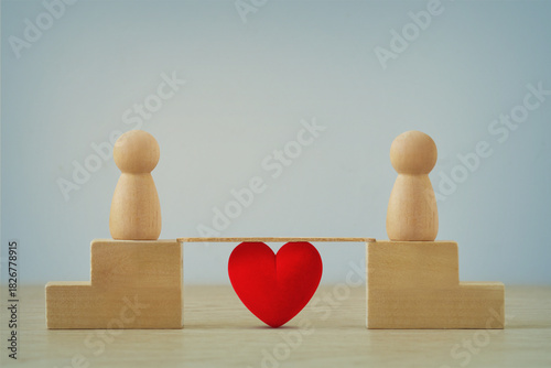 Two distant wooden pawns joined by a brige with heart - Concept of love and distance