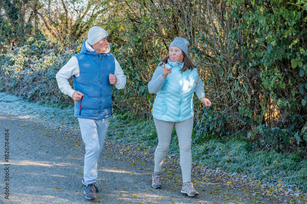 Fototapeta premium happy senior couple jogging on frosty path, cool weather, morning jog, active lifestyle, healthy enjoying active aging together sports, fitness during, healthier routine in nature, daily exercise