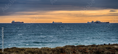 Fototapeta Naklejka Na Ścianę i Meble -  Sunset Over The Ocean With Distant Ships And Coastal Dunes On A Calm Horizon Today, Skagen, Denmark