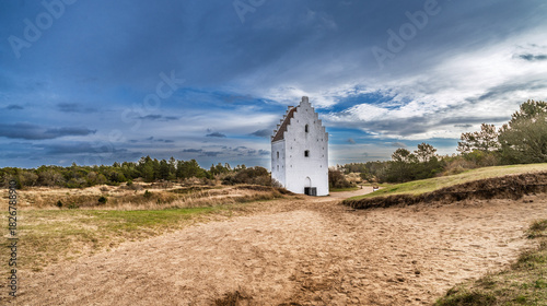 Foto White Historic Church Tower Standing Alone in Dune Landscape Under Bright Blue S