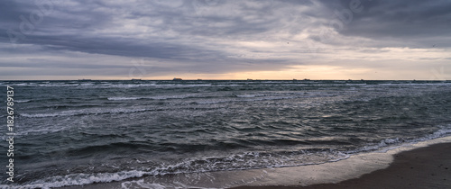 Fototapeta Naklejka Na Ścianę i Meble -  Sunset Over The Ocean With Distant Ships And Coastal Dunes On A Calm Horizon Today, Skagen, Denmark