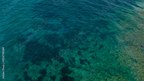 Aerial perpendicular view of the sea surface. The ocean's colors range from turquoise to blue. Ideal for backgrounds, textures and patterns.