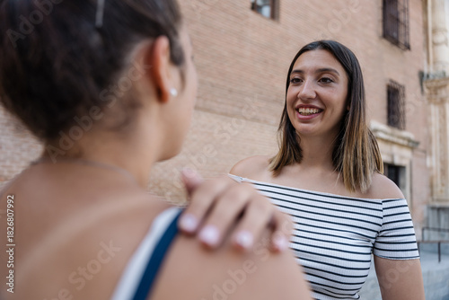 Slika na platnu Two young women sharing a moment of friendship in urban setting