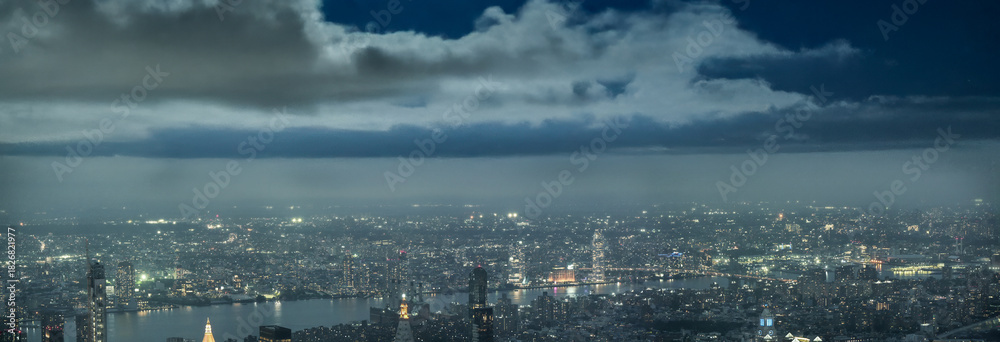 Obraz premium Drone panorama of Manhattan cityscape illuminated by evening lights after sunset over New York City