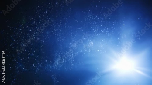 Wallpaper Mural A bright light source in a deep blue space with particles suspended, suggesting an underwater scene Torontodigital.ca