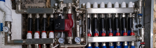 Complex residential heating manifold system with valves, gauges, and piping network. banner