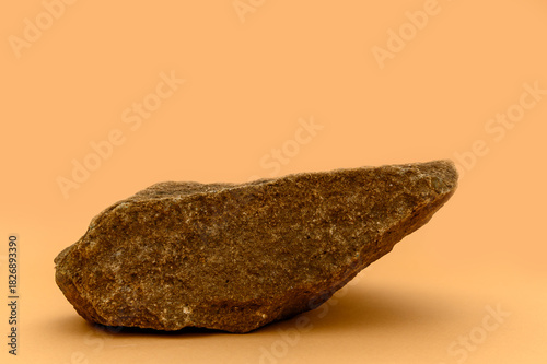 A large brown stone on a beige background. Product display podium.