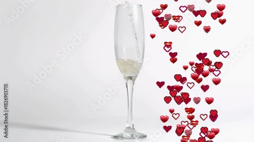 Tall champagne flute receiving pale pouring from above causing red hearts rising beside evoking joy