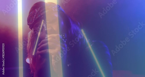 Female singer holding mic and singing on stage, neon bars sweeping across face, bandana showing