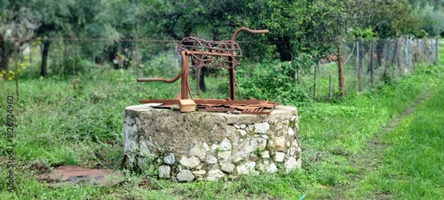 Old Rusty Traditional Water Well in Rural Landscape