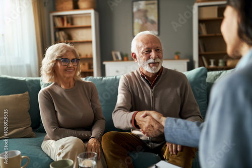 Happy mature couple  came to an agreement with female advisor on sofa in the living room