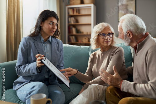Female layer and senior couple going through a contract during a meeting in the living room.