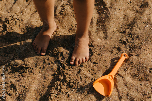 Children's feet in the sand on the beach.