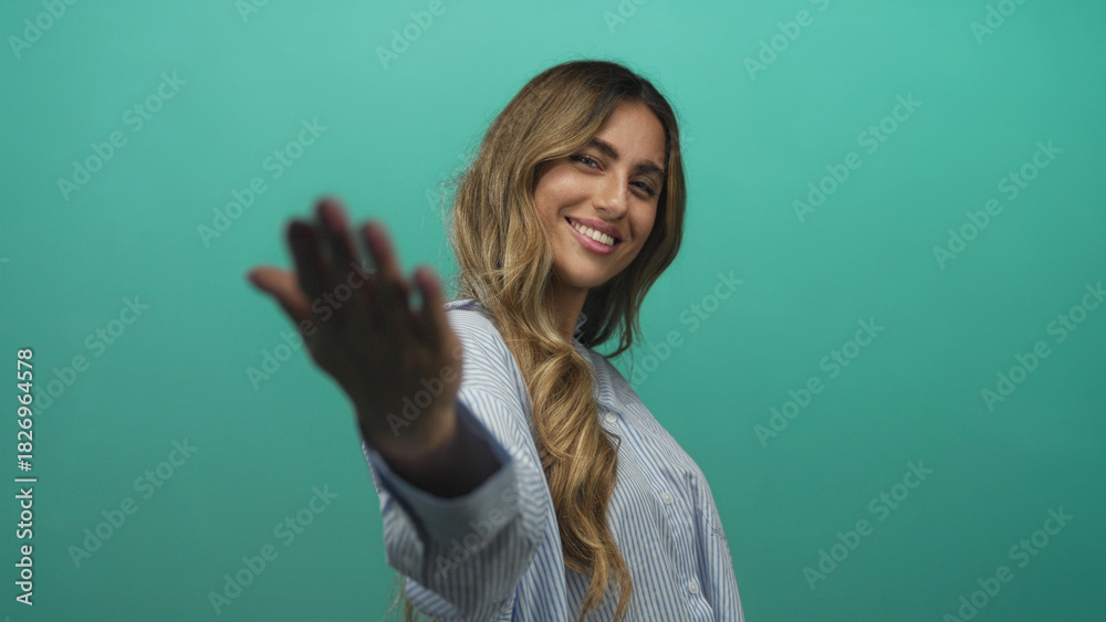 Fototapeta premium Blonde young woman smiling and showing open palms in photo studio; invitation welcome friendliness openness.