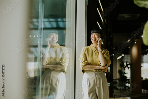 Professional woman smiling while talking on phone in modern office setting