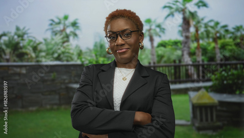 Wallpaper Mural Woman adjusts her jacket with a subtle smirk amidst lush green trees and palms in a forest setting; confidence. Torontodigital.ca