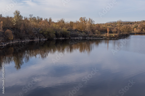 Abandoned granite quarry lake with reflective water and rocky cliffs in warm natural evening light