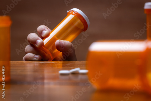 A powerful conceptual photograph showing a child's hand reaching for colorful, unattended prescription pills or medication.