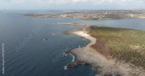 Aerial view of the coast of Capo Passero Island, an Italian island located in the Mediterranean Sea. In the background, the village of Portopalo di Capo Passero, Sicily, Italy.