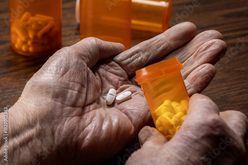 A detailed close-up shot of wrinkled, elderly senior hands carefully dosing pills from a prescription bottle.