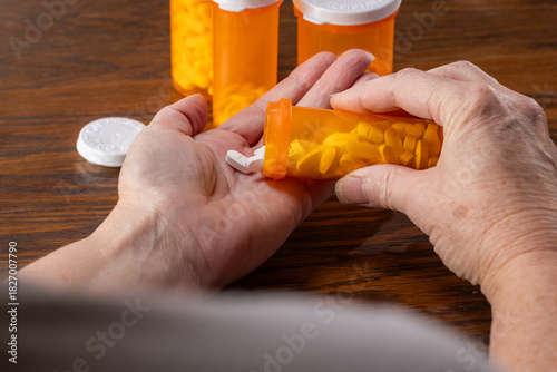 A third-person view showing the hands of a person dispensing a daily dose of pills from a bottle, surrounded by multiple prescription bottles.