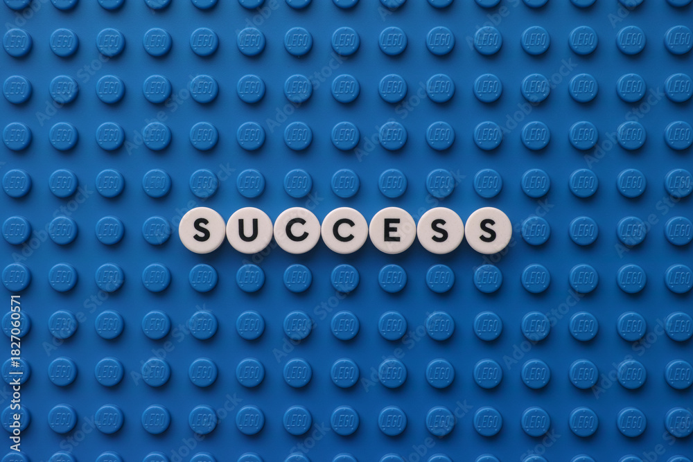 Naklejka premium Tambov, Russian Federation - November 24, 2025 The word Success on a blue Lego baseplate. The scene is made out of Lego dots.