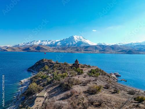 Spectacular aerial photograph of Akdamar Island and the Holy Cross Cathedral on Lake Van, Turkey. The historic church stands out against the deep blue lake and the majestic, snow-capped Süphan Mountai