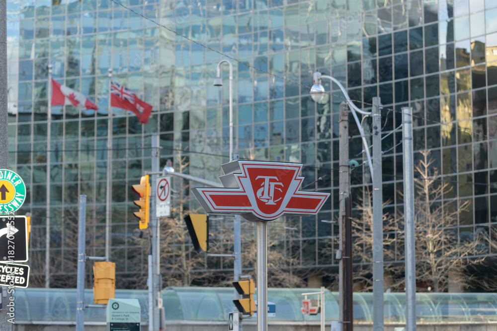 Fototapeta premium Toronto Transit Commission logo sign at College / Queen's Park station, line 1, with office tower behind (700 University Av)