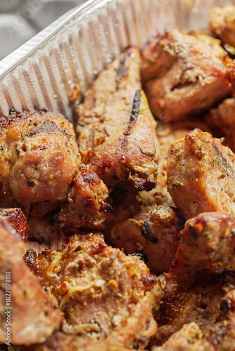 Close-up of grilled shashlik kebab pieces in a foil tray