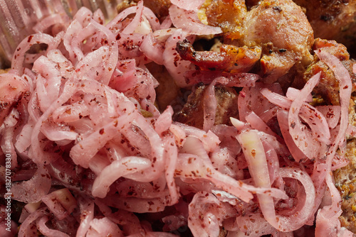 Close-up of grilled shashlik kebab pieces with marinated onions in a foil tray