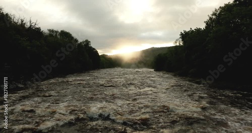 Flying over a river at sunrise