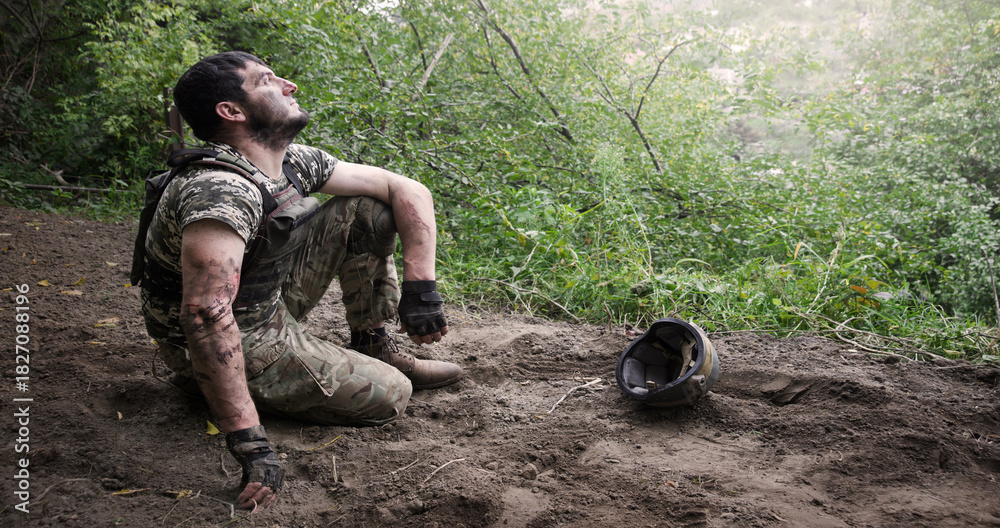 Fototapeta premium Young soldier sitting on the ground