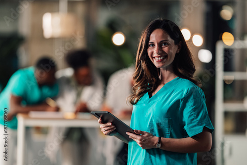 Female doctor nurse holding tablet smiling at camera