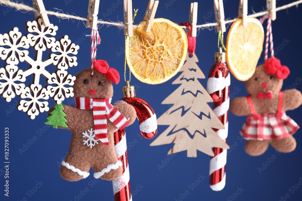 Naklejka premium Different Christmas decor hanging on string against blue background, closeup. New Year greeting card