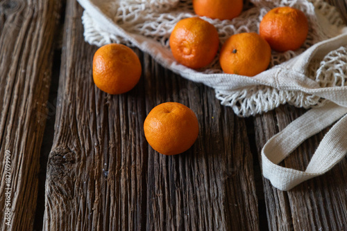 oranges on a wooden table in reusable bag
