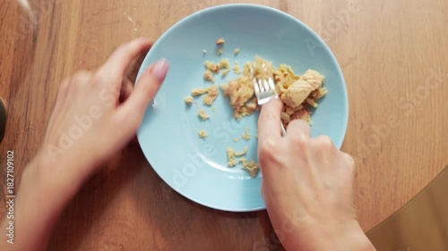 A hand digs into a bowl of creamy peanut butter on a wooden table