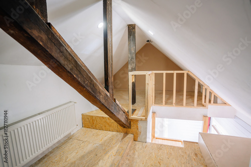 Interior view of a modern loft space showcasing wooden beams, open staircase, and unfinished walls, highlighting the potential for creative design and renovation projects
