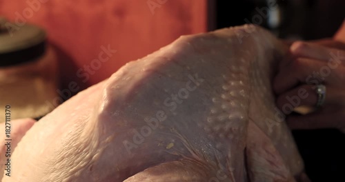 Woman rubbing butter under the skin of a turkey for Thanksgiving dinner. 