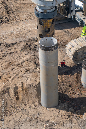 Wallpaper Mural Overhead view of dusty construction site showing heavy machinery with large drilling rig and steel casing segments being installed for deep pile foundations in excavated earth. Torontodigital.ca