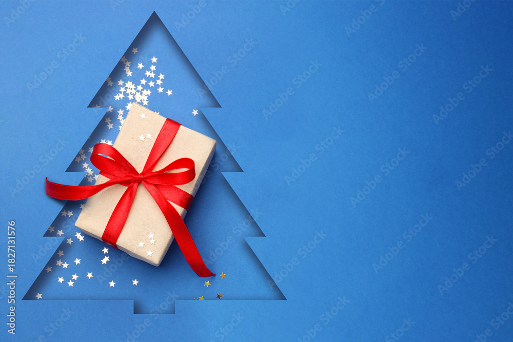 Obraz premium Merry Christmas and Happy New Year! Greeting card with Christmas tree cut in blue paper, confetti and gift box
