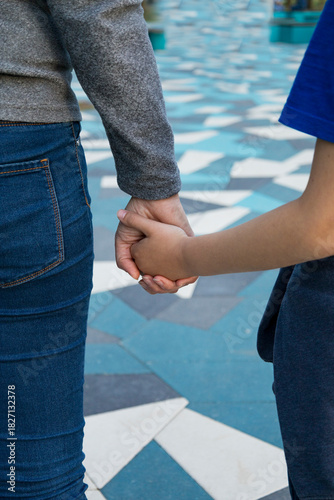 Closeup of couple on city mosaic tiles, Casual couple holding hands amidst textured urban environment, Intimate partners in casual clothing connecting during candid city walk